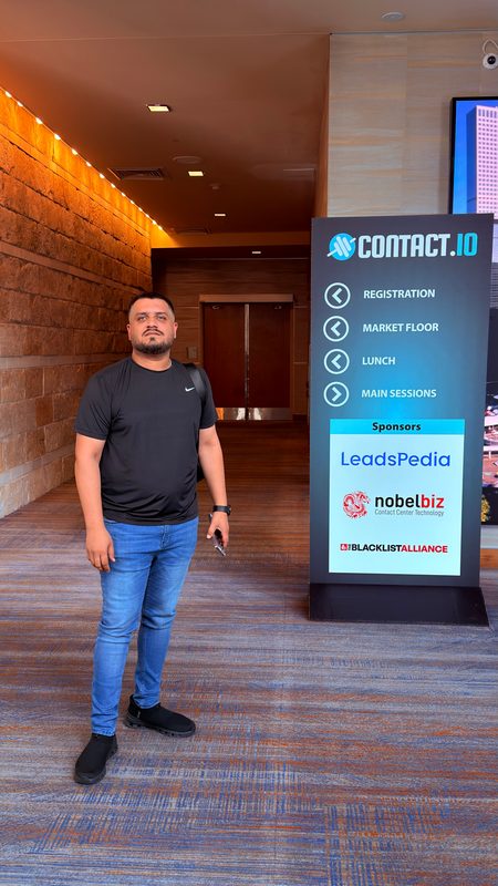 Wali Zuberi, Founder of ZW Global Group, beside a wayfinding sign at Contact.io 2026 in Denver