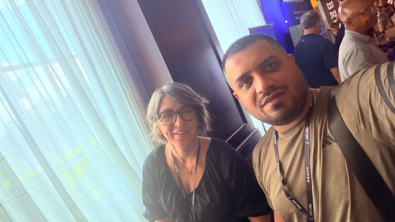 Selfie of Wali Zuberi with a fellow attendee beside a window at MedicareCon 2026
